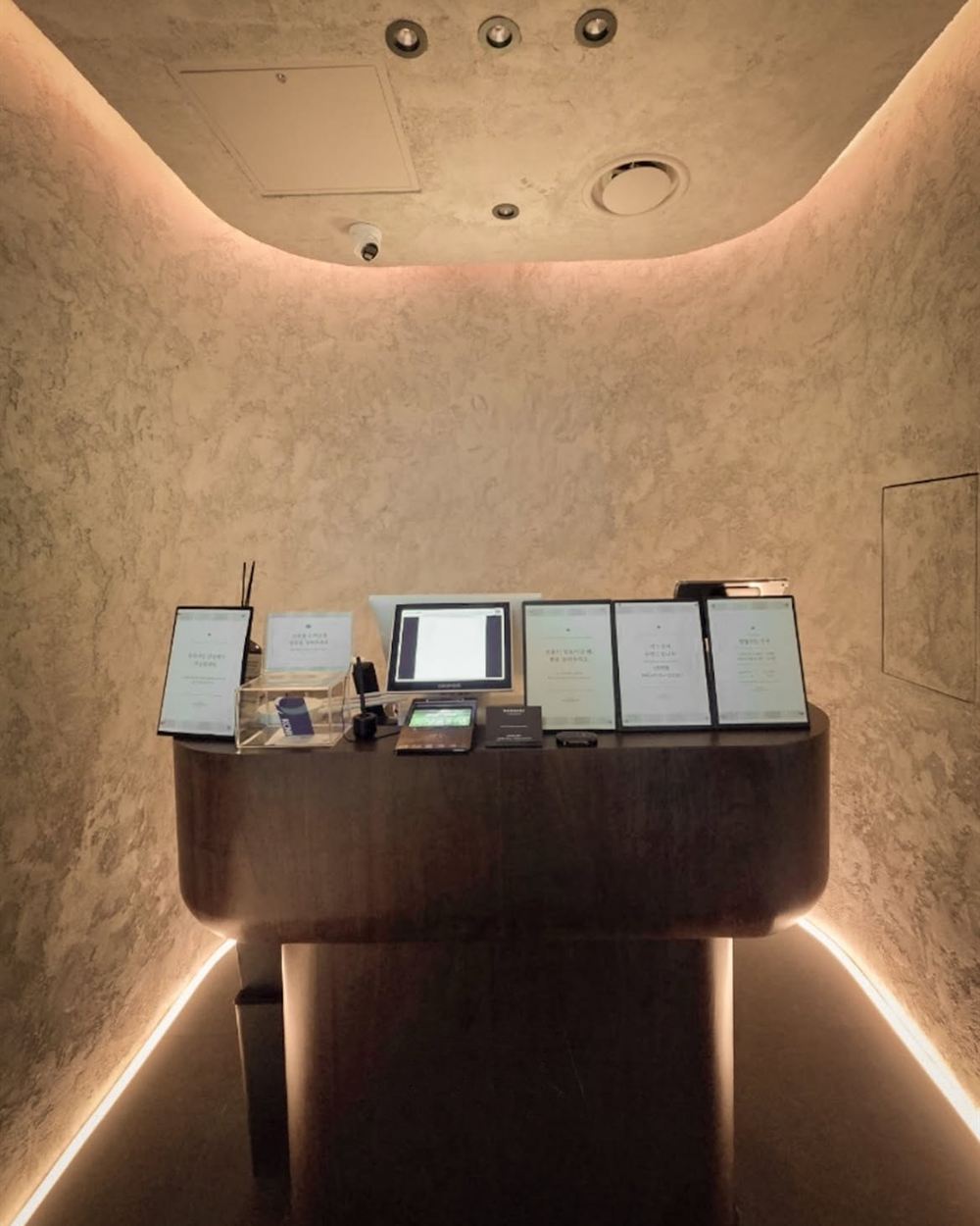 은은한 조명 아래 유럽미장으로 마감한 안내 데스크 공간